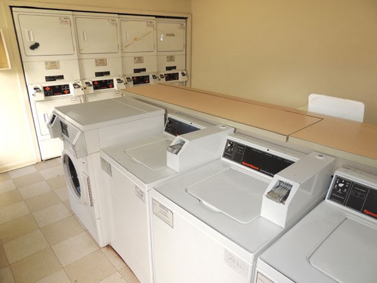 Cornerstone Apartments interior of laundry facility washer and dryers, pay with quarters, folding table area