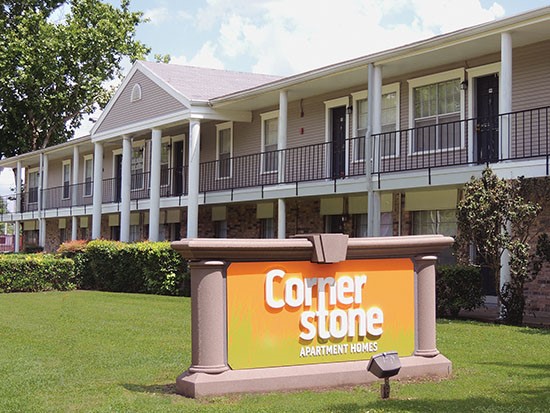 Cornerstone Apartments huge bright orange sign with white letters leading into apartment complex