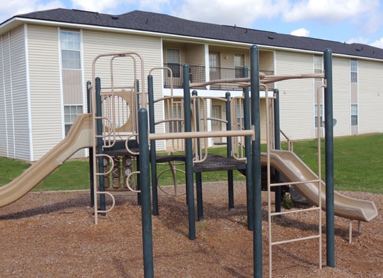 Fox Creek Apartments green and tan playground with slides and monkey bars