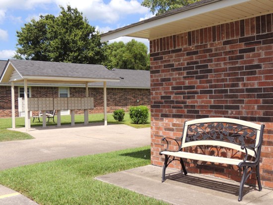Heritage Village corner of front office building with bench, mailboxes with overhead shade