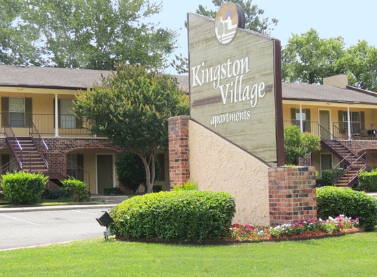 Kingston Village Apartments Huge and tall green and brick front sign entering into apartment complex