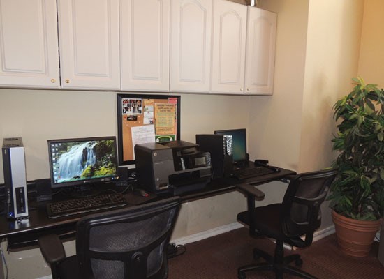 La Crosse Apartments business center interior with desk and laptops