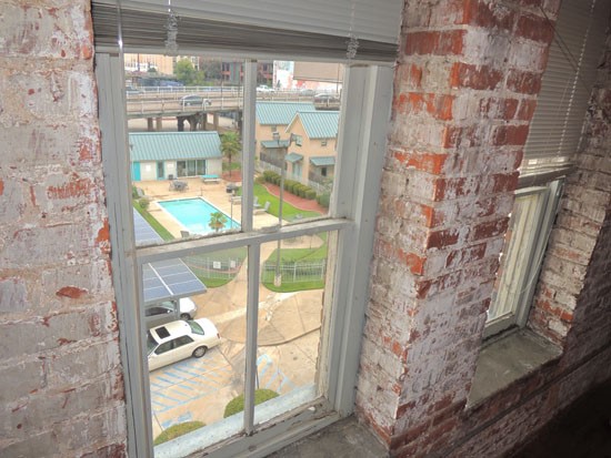 Lee Hardware looking out of window from inside apartment in downtown shreveport