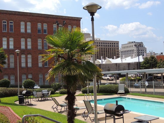 Lee Hardware outside pool area with nice trees, grill and pool side lounge chairs