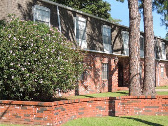 Park Villa front side view of two story brick and brown apartment building shaded by trees