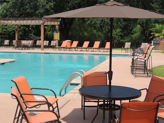 Riverbend Apartment pool with overhead umbrella seating area with table and chairs
