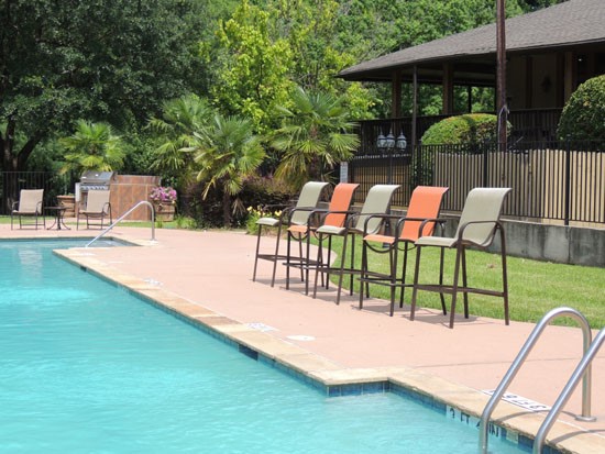 Riverbend Apartments gated pool, steps leading into pool, high pool side lounge chairs
