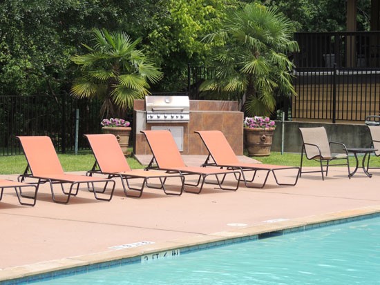 Riverbend pool side view of lay down pool side lounge chairs and large grill to cook