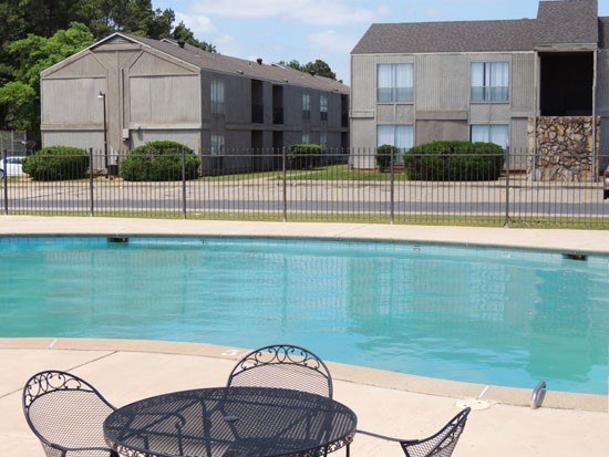Tree Tops Apartments pool side view of pool with tables and chairs and apartments in background